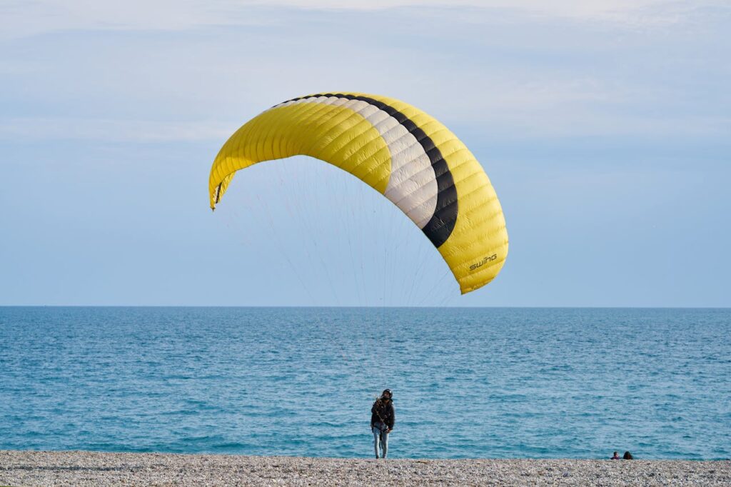 A person paragliding on a picturesque beach, capturing a summer adventure on the shore.