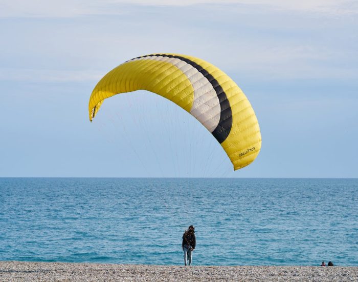 A person paragliding on a picturesque beach, capturing a summer adventure on the shore.